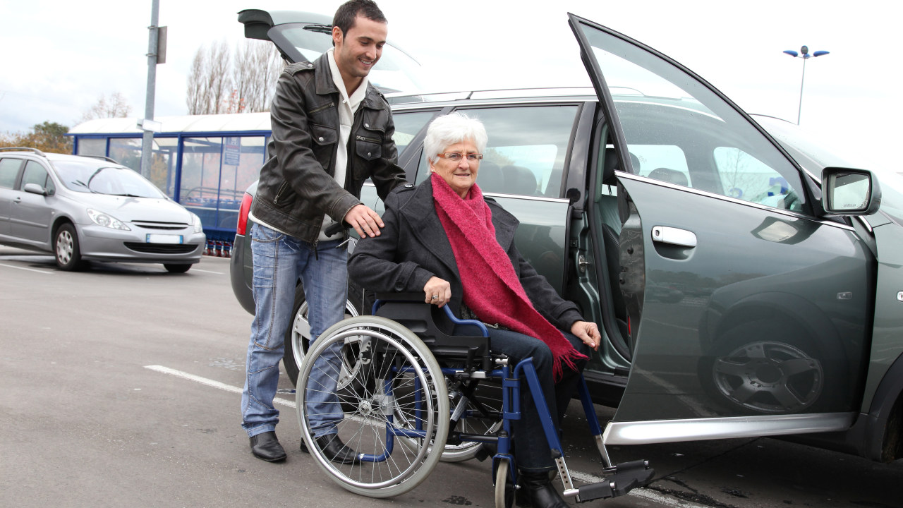 mann hjelper eldre kvinner i rullestol