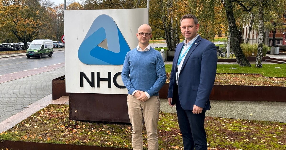 To personer foran NHOs logo ved Næringslivets Hus