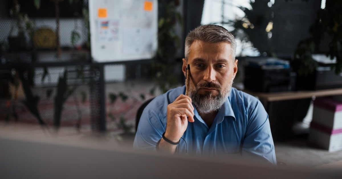 tankefull leder tygger på en penn foran en pc