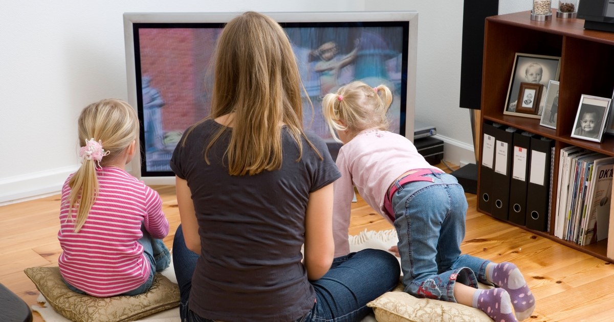 Barnevakt med to barn foran TV