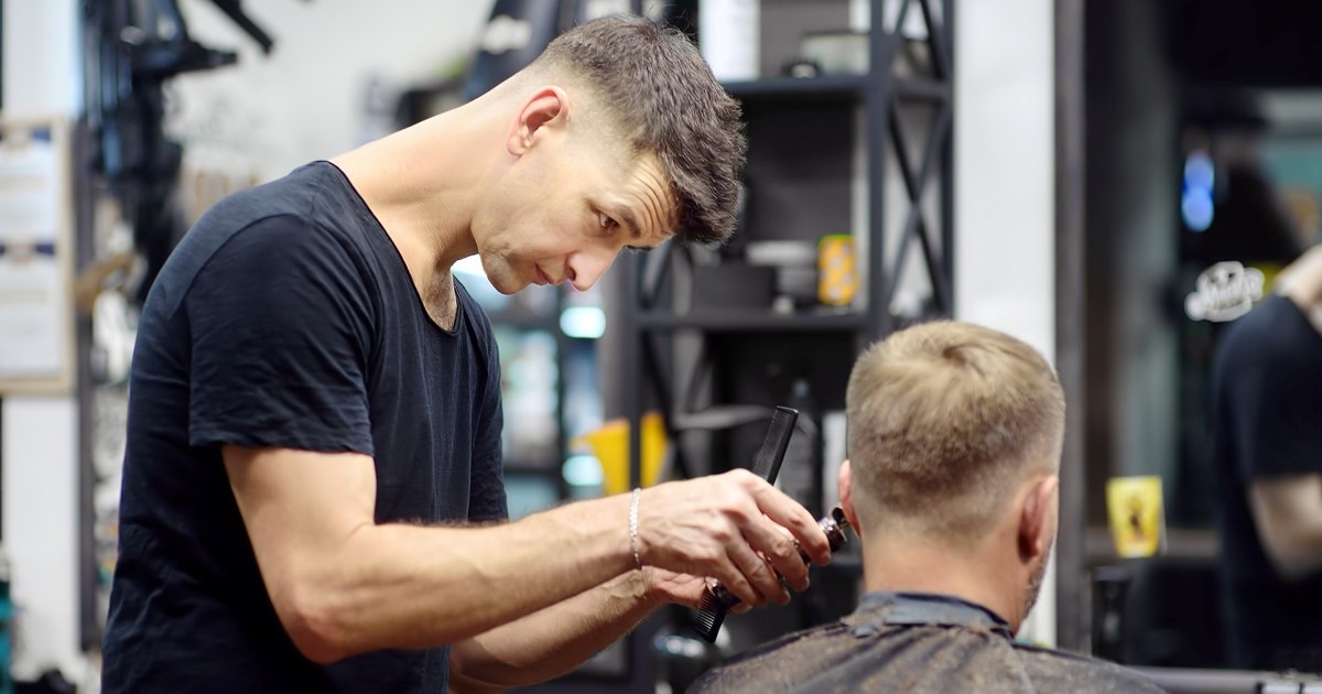 Mannlig frisør klipper hår
