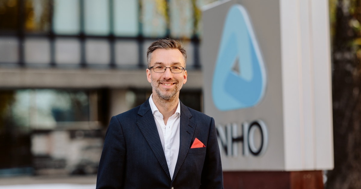 Person i dress foran NHO-logo