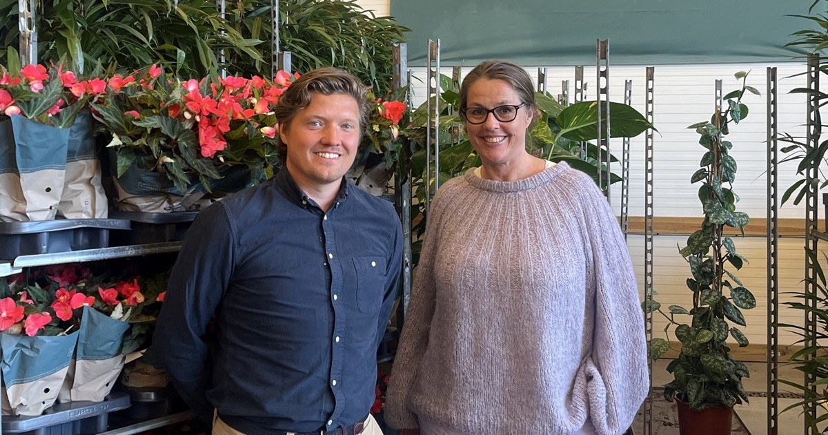 Kvinne og mann foran blomster og plakaten Mester Grønn